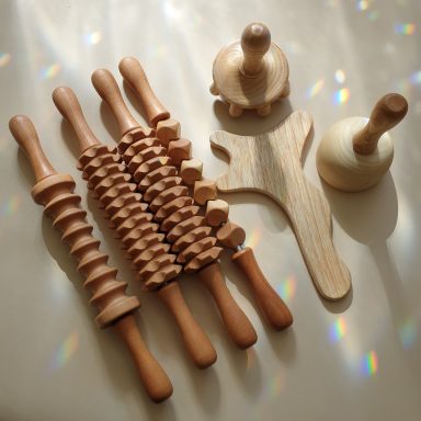 Diverse Holzroller und -formen auf einer glatten Oberfläche mit Lichtreflexionen.