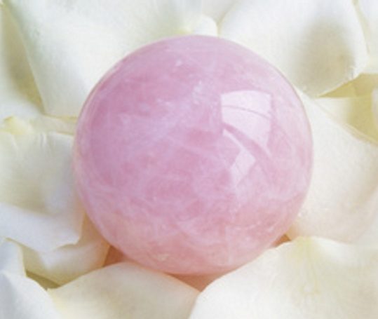 Rosa Quarz-Kugel auf weißen Blütenblättern.