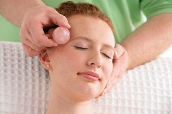 Frau erhält eine Gesichtsbehandlung mit einer Massage und einem Massagegerät.